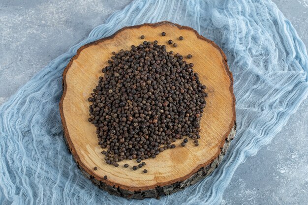 A wooden board full of dried peppercorns. 