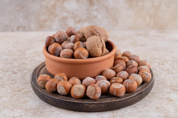 A wooden board full of healthy macadamia nuts .