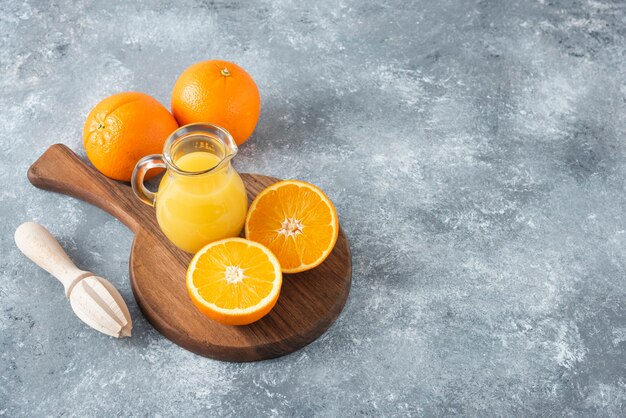 A wooden board full of juicy slices of orange fruit on stone table .