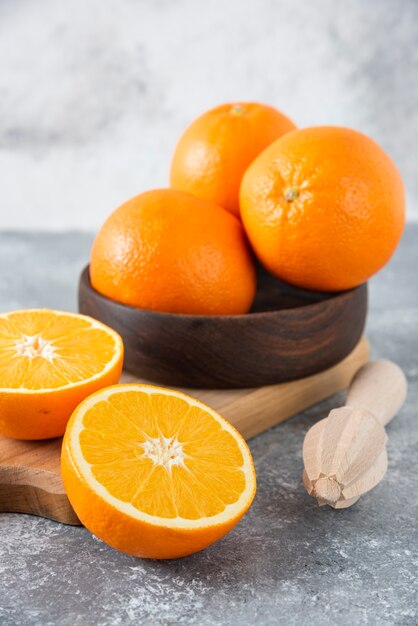 Деревянная доска, полная сочных ломтиков апельсина на каменном столе.