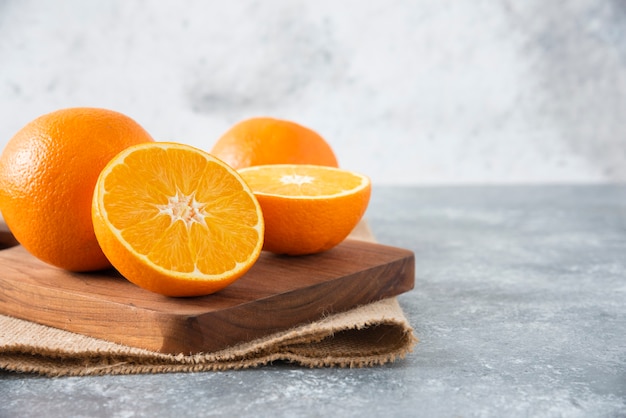 A wooden board full of juicy slices of orange fruit on stone table .