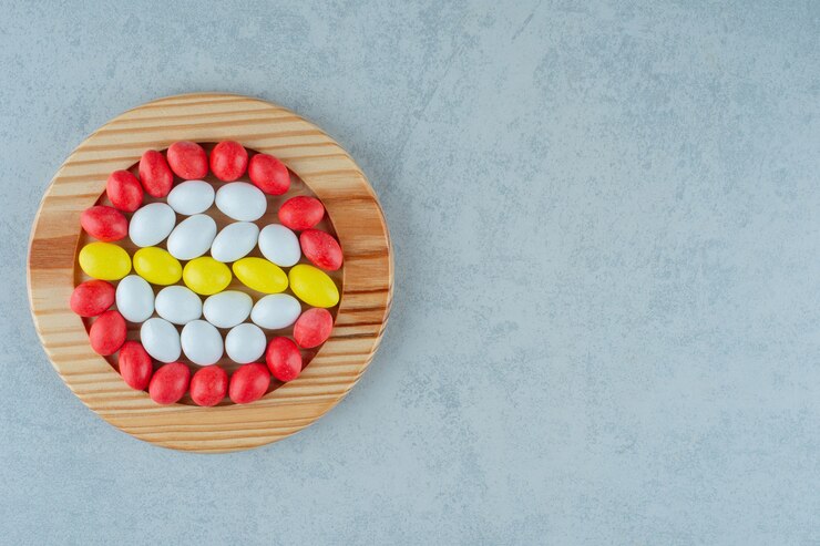 Free Photo a wooden board full of round sweet colorful candies on white surface