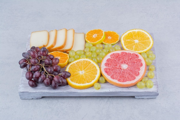 Free photo a wooden board full of sliced fruits and bread . high quality photo