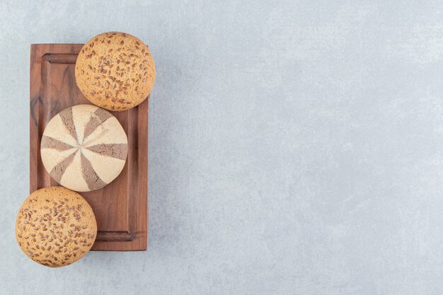 A wooden board full of sweet cookies .  