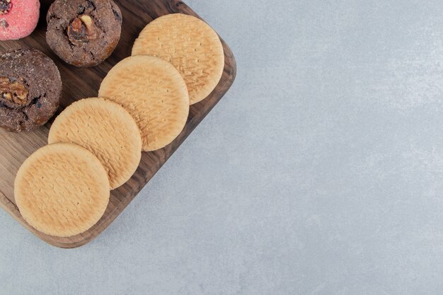 A wooden board full of sweet cookies .  