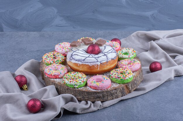 A wooden board full of sweet donuts and Christmas balls