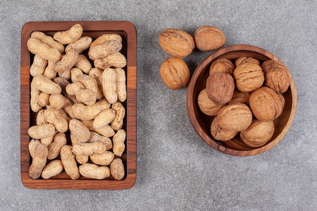 A wooden board of healthy peanuts and walnuts in shell