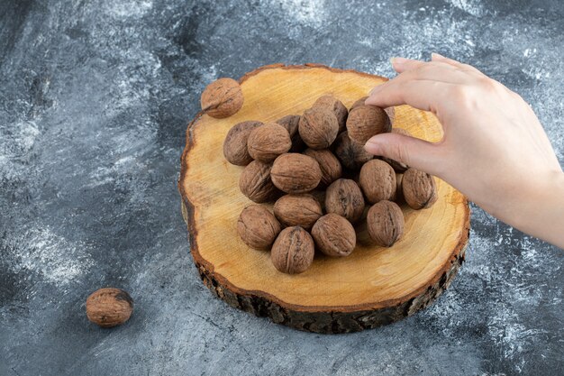 A wooden board of healthy walnuts on a gray surface.