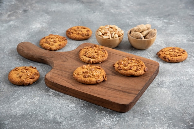 Wooden board of homemade cookies with organic peanuts on marble table. 