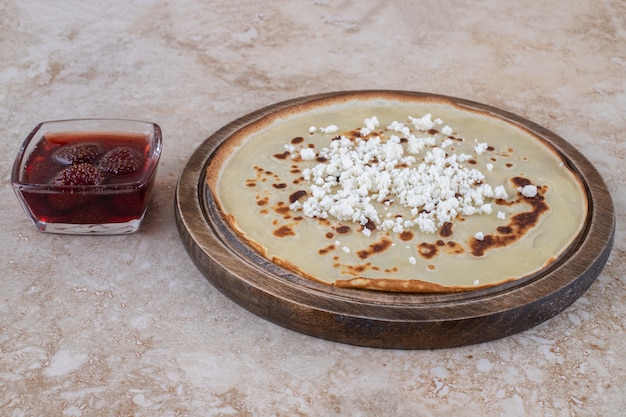 A wooden board of homemade thin fresh crepes with strawberry jam 
