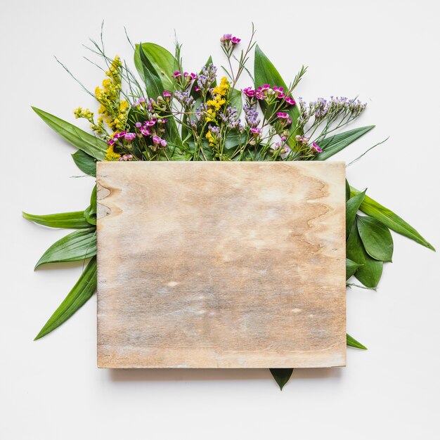 Wooden board on leaves and flowers