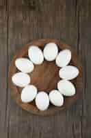 Free photo wooden board of raw organic eggs on wooden surface.