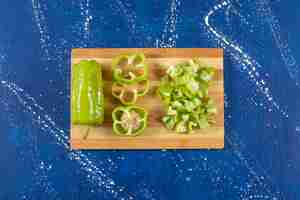 Free photo wooden board of sliced green bell peppers on marble surface