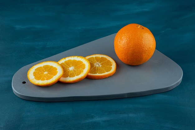 青い表面にスライスしたジューシーなオレンジの木の板。
