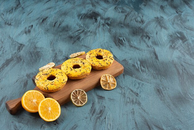 Free photo a wooden board of sweet doughnuts with fresh sliced lemon and dried slices