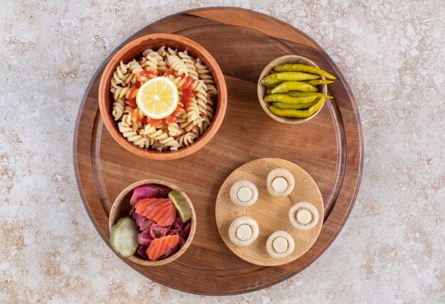 A wooden board of tasty pasta with mushrooms and spices