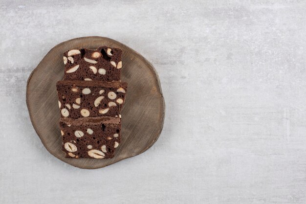 Wooden board with brown bread slices with nuts on a stone table. 