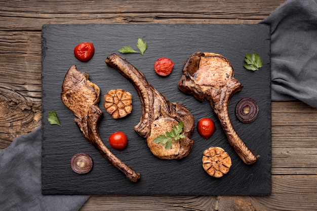 Wooden board with cooked meat and vegetables