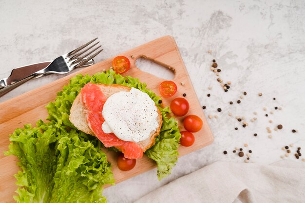 Wooden board with fresh sandwich on table