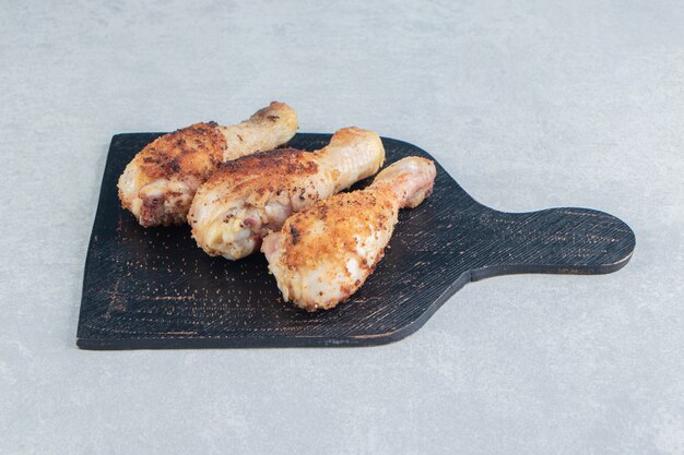 A wooden board with fried chicken legs meat. 