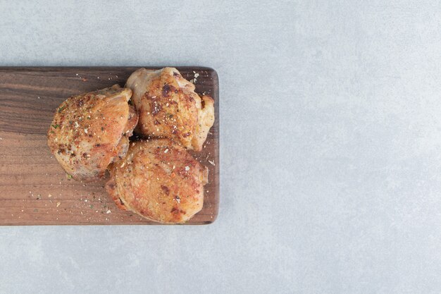 A wooden board with fried chicken meat with relish . 