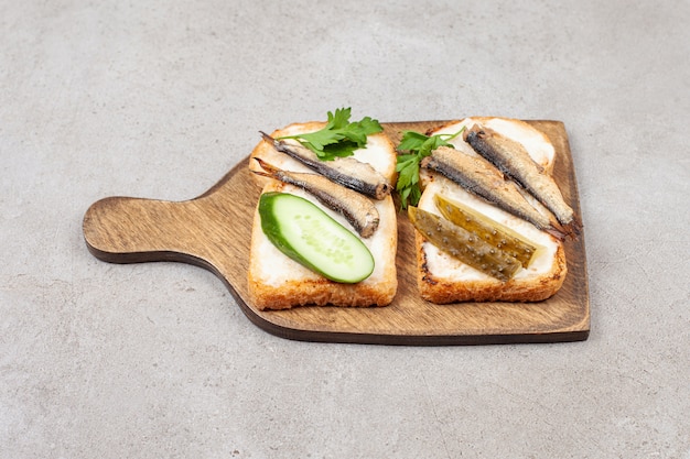 A wooden board with fried toasts and sprats 