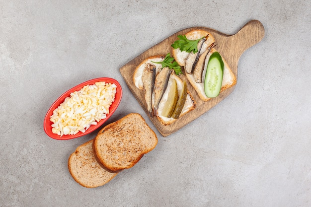 A wooden board with fried toasts and sprats 