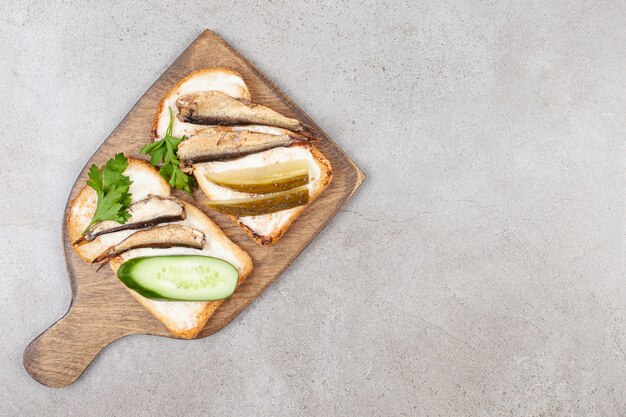 A wooden board with fried toasts and sprats 