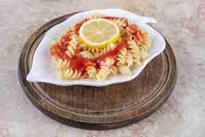 Foto gratuita tavola di legno con un piatto di pasta al limone sulla superficie in marmo