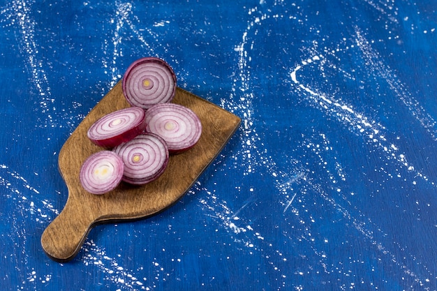 Free photo wooden board with purple onion rings on marble surface
