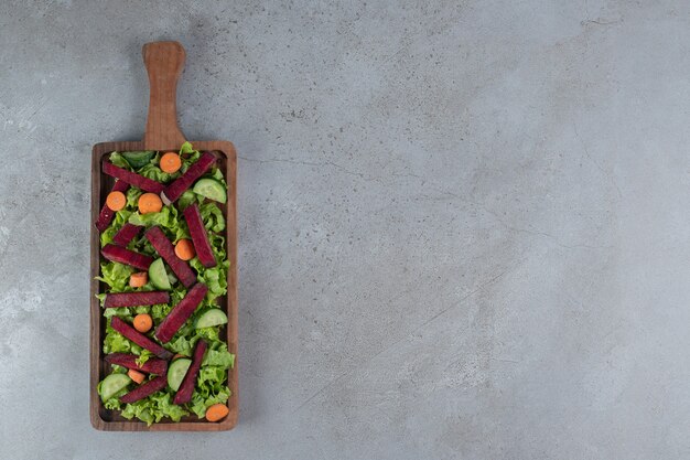 회색 배경에 야채 샐러드가 있는 나무 보드. 고품질 사진