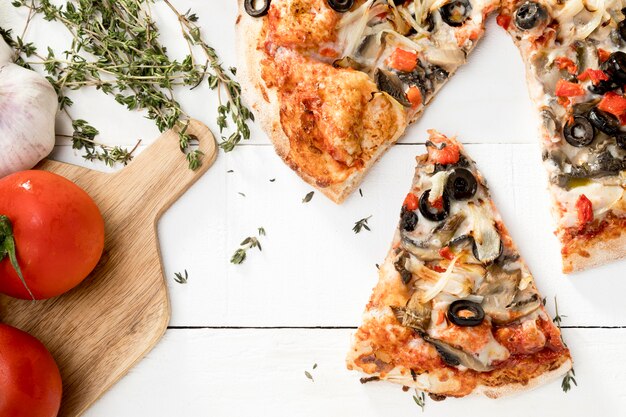 Wooden board with vegetables and pizza