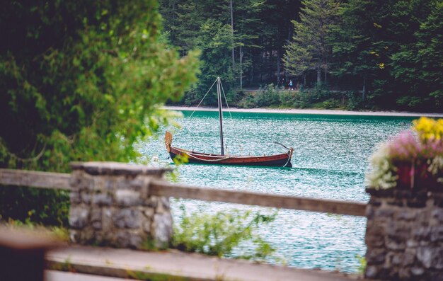 A wooden boat on the water surrounded by greenery under the sunlight