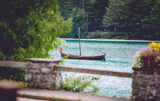 A wooden boat on the water surrounded by greenery under the sunlight