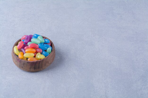 A wooden bowl of colorful sweet jelly bean candies . High quality photo