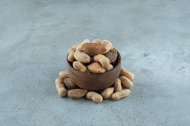Wooden bowl of crispy peanuts placed on stone background
