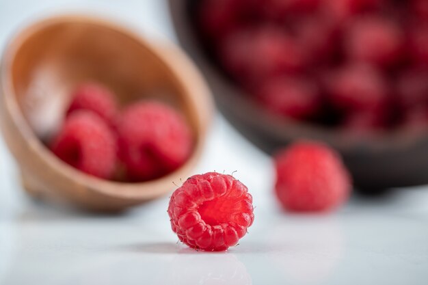 Wooden bowl of delicious healthy raspberries on stone table