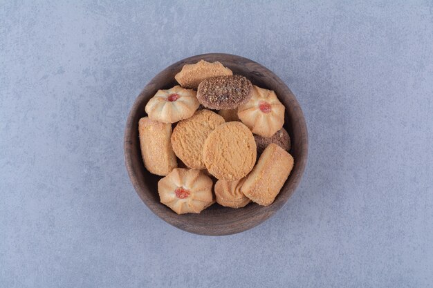 A wooden bowl of delicious sweet cookies . 