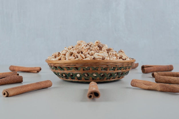 A wooden bowl full of healthy cereals with cinnamon sticks .