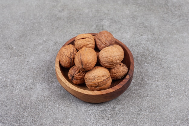 A wooden bowl full of healthy walnuts in hard shells