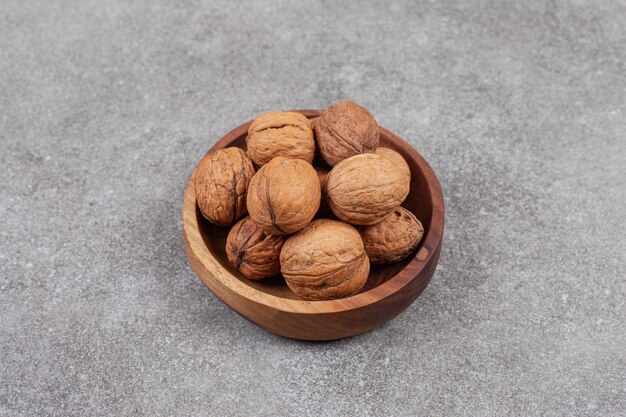 A wooden bowl full of healthy walnuts in hard shells