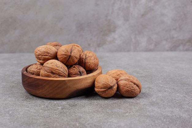 A wooden bowl full of healthy walnuts in hard shells