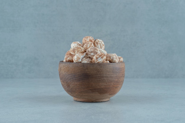 A wooden bowl full of sweet delicious gingerbread on white surface