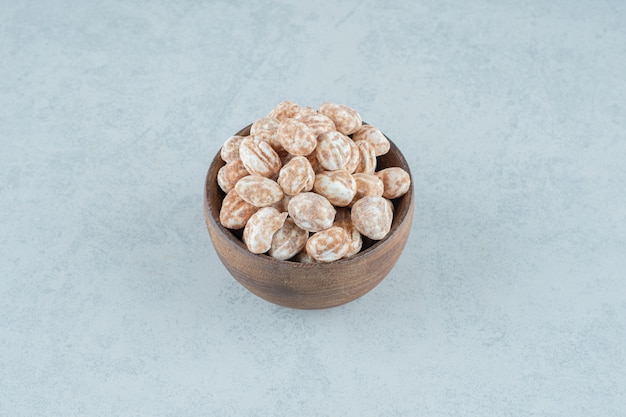 A wooden bowl full of sweet delicious gingerbread on white surface