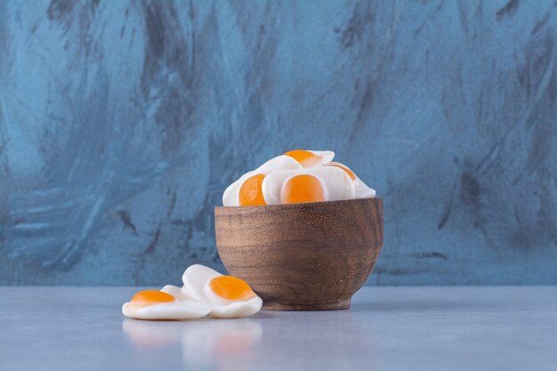 A wooden bowl full of sweet jelly-fried eggs on gray table . 