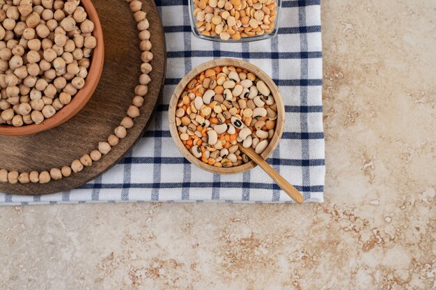 A wooden bowl full of unprepared peas with spices and beans .