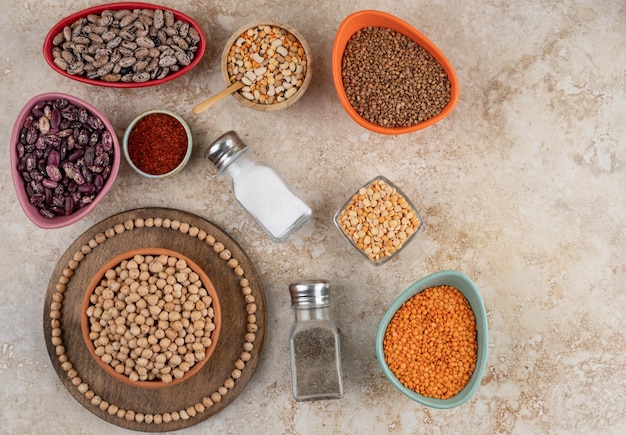 A wooden bowl full of unprepared peas with spices and beans .