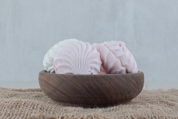 Free photo a wooden bowl full of white and pink zephyrs .