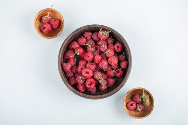 wooden bowl of healthy delicious raspberries on stone surface