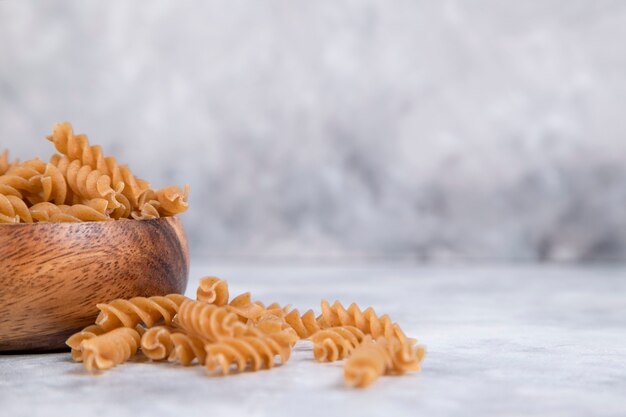 A wooden bowl of Italian uncooked dry pasta Fusilli . High quality photo